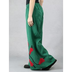 Green linen trousers with wide Swedish legs, decorated with sewn flowers.