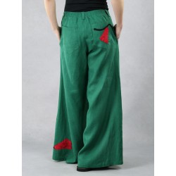 Zielone spodnie lniane z szerokimi nogawkami typu szwedy, ozdobione naszywanymi kwiatami.