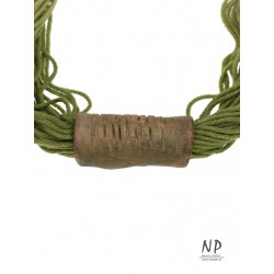 W odcieniu zielonym naszyjnik sznurkowy z ceramiczną ozdobą w kształcie rurki.