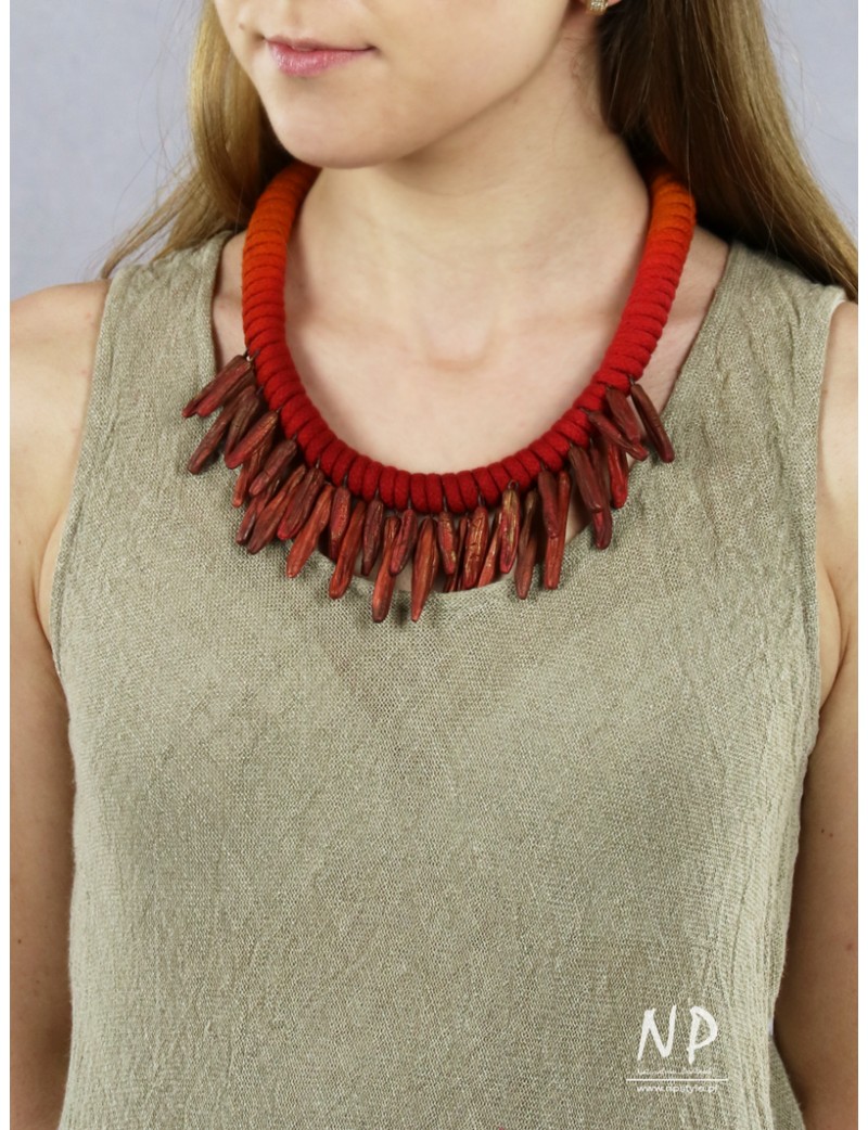 In a shade of red and orange, a handmade necklace made of cotton string and ceramic ornaments