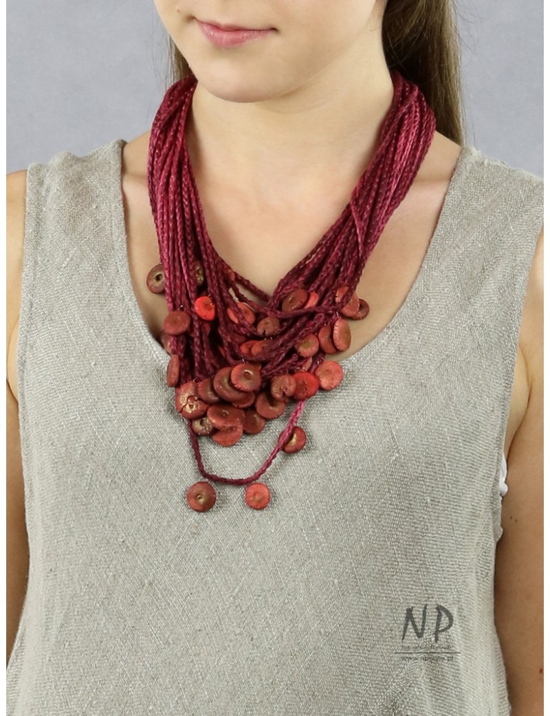 In the colors of burgundy and dirty pink, a handmade necklace made of linen and cotton strings decorated with ceramics