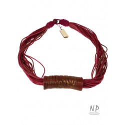 A handmade string necklace with a ceramic tube