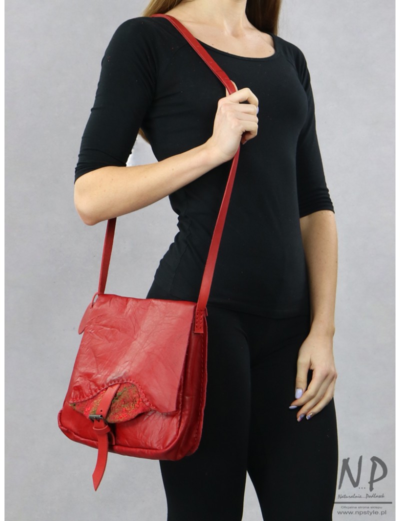 A small red women's handbag made of natural leather with a decorative flap