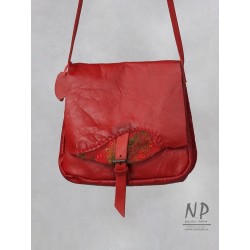 A small red women's handbag made of natural leather with a decorative flap