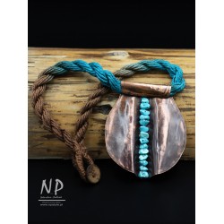 Handmade necklace made of linen strings decorated with a pendant made of copper and small turquoises