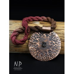 Handmade necklace made of linen strings decorated with an original round pendant made of copper and amber