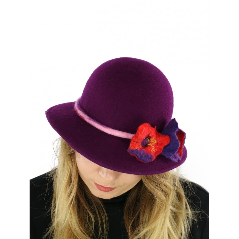 A felt hat with a large purple brim, decorated with felted flowers.